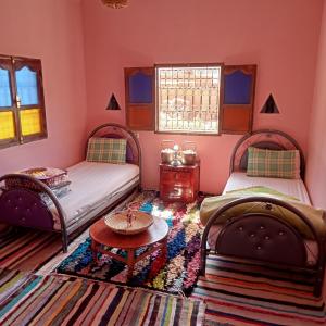 a room with two beds and a table in it at Dar Brahim tizgui nbarda in Ouarzazate