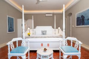 a bedroom with a white bed and two chairs at Villa Cavi in Puducherry