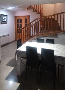 una mesa y sillas en una habitación con escalera en Casa Rosa, en Alcañiz