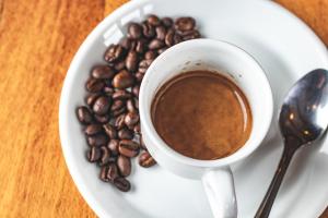 a cup of coffee on a plate with coffee beans at Hotel Museo El Greco Puerto Varas in Puerto Varas
