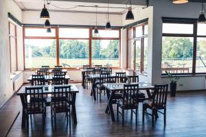 un ristorante con tavoli, sedie e ampie finestre di Penzion Kamence a Liptovský Mikuláš