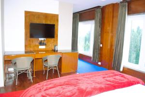 1 dormitorio con 1 cama y escritorio con sillas en PinnacleHouse kanatal Uttarakhand, en Kanatal