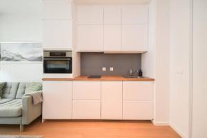 a kitchen with white cabinets and a couch at Luxury apartment in city center in Bratislava