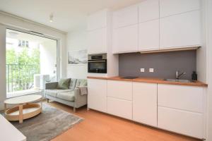 a kitchen with white cabinets and a living room at Luxury apartment in city center in Bratislava