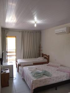 1 dormitorio con 2 camas y ventana en Pousada Sitio Paraíso en Cabo de Santo Agostinho