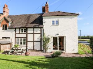 a white house with large windows and a yard at Bluebell Cottage in Rugeley