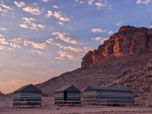 two buildings in the desert with a mountain in the background at Wadi Rum Camp & Jeep Tour in Wadi Rum