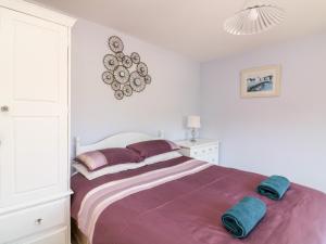 a white bedroom with a large bed with purple sheets at Thornberry in Salcombe