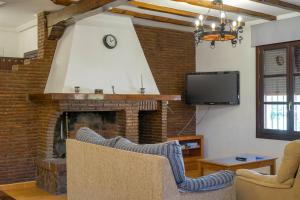 un salon avec une cheminée et une télévision dans l'établissement La Masía casa rural junto al río, à Almedinilla