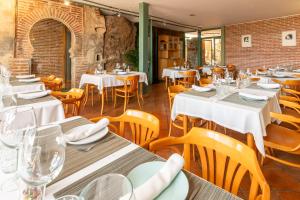 um restaurante com mesas brancas e cadeiras de madeira em Hospedería el arco em Villavieja del Lozoya