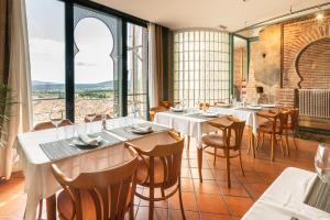 um restaurante com mesas e cadeiras e janelas grandes em Hospedería el arco em Villavieja del Lozoya