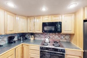 a kitchen with wooden cabinets and a stove and a microwave at Summit House East 113 in Copper Mountain