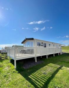 a large white mobile home on a grass field at Marianne Bay - Southerness Caravan Park with Sea View - Pet Friendly in Mainsriddle