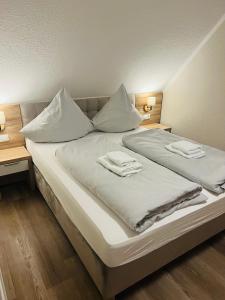a large white bed with two towels on it at Hotel Seewiefken in Wangerland