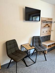 dwa krzesła i stół w pokoju z telewizorem w obiekcie Gästehaus Schöpf Elsa w Langenfeld