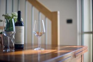 uma garrafa de vinho e um copo sobre uma mesa em Trevisan Loft: Slow Food, Langhe, and Comfort em Bra