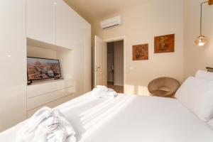een witte slaapkamer met een wit bed en een televisie bij Residenza del Principe - DB Apartment in Florence