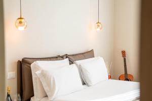 een slaapkamer met een bed met witte kussens en een gitaar bij Residenza del Principe - DB Apartment in Florence