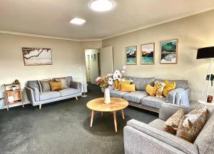 a living room with two couches and a table at Free-Range On Papmoa Beach in Tauranga