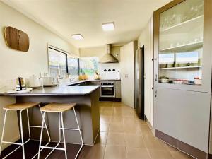 a kitchen with a counter and stools in it at Free-Range On Papmoa Beach in Tauranga