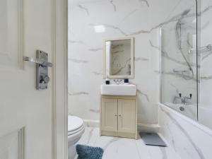 Baño blanco con lavabo y aseo en Stoke On Trent - City Centre, Ideal for contractors, families, and business travelers By Doko Homes en Stoke on Trent