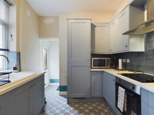 una cucina con armadi bianchi e lavandino di Stoke On Trent - City Centre, Ideal for contractors, families, and business travelers By Doko Homes a Stoke on Trent