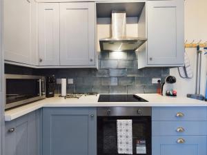 a kitchen with blue cabinets and a stove top oven at Pottery House - Stoke on Trent -Free parking - Central Location - Sleep 8 in Stoke on Trent +32 photos