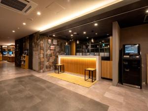 a lobby with a counter with two stools and a bar at Super Hotel Fujikawaguchiko Tennenonsen in Fujikawaguchiko