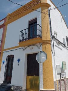 Edificio amarillo y blanco con balcón en ALOJAMIENTO RURAL AN CA LA ABUELA PILAR, en El Real de la Jara