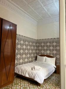 een slaapkamer met een bed in een kamer met een muur bij Riad Del Rey in Rabat