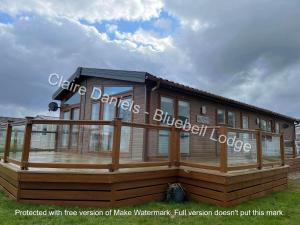 a large wooden house with a large deck at Bluebell Luxury 2 Bedroom Lodge at Southview Holiday Park in Skegness