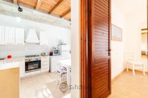 una cocina con armarios blancos, una mesa y una puerta en Casa Nicole - Near the Beach, en Geremèas
