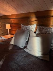 ein Schlafzimmer mit einem Bett mit Kissen und einer Lampe in der Unterkunft "SoFly Lodge", Charm and Elegance in Noresund