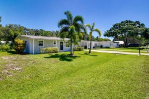 a house with palm trees in a yard at Dog-Friendly Vero Beach Retreat with Porch and Grill! in Vero Beach