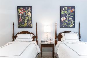 2 Betten in einem Schlafzimmer mit Gemälden an der Wand in der Unterkunft Biddle Point Inn in Plymouth