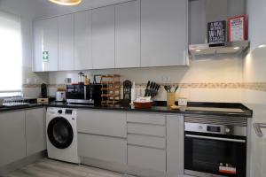 uma cozinha com armários brancos e uma máquina de lavar louça em Catita Home em Vila Nova de Cacela