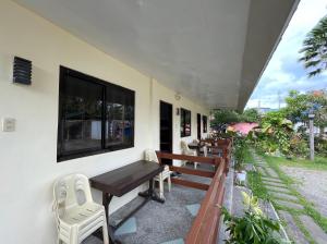 a patio with a wooden table and chairs and a window at Jamjens Lodge powered by Cocotel in Baler