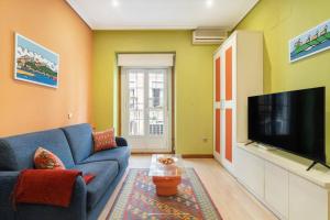 uma sala de estar com um sofá azul e uma televisão de ecrã plano em Victor Apartments Chueca II em Madri