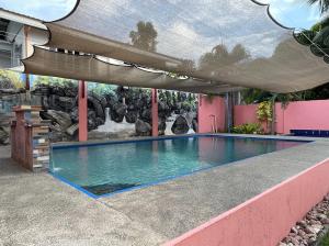 a swimming pool with an umbrella over it at Jamjens Lodge powered by Cocotel in Baler