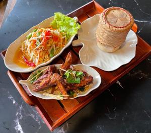 zwei Teller Essen auf einem Holztablett in der Unterkunft Pen's Bungalow Koh Phangan in Thong Nai Pan Yai
