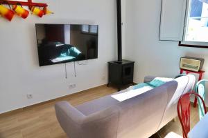 uma sala de estar com um sofá e uma televisão de ecrã plano em Sítio DaTerra em Santo António da Terrugem
