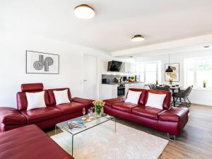 a living room with red leather couches and a table at FeWo Prora - Oase in Binz