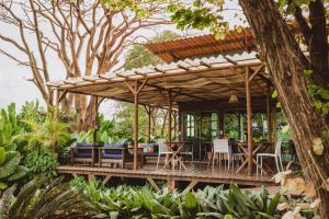 une pergola en bois avec des tables et des chaises sur une terrasse dans l'établissement Pousada Moana, à Fernando de Noronha