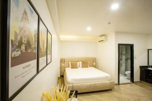 1 dormitorio con 1 cama y algunas fotos en la pared en Phuoc Thanh IV Hotel en Vĩnh Long