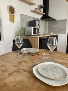 una mesa de madera con dos platos y copas de vino en Logement Merida de Rouen - 063, en Rouen