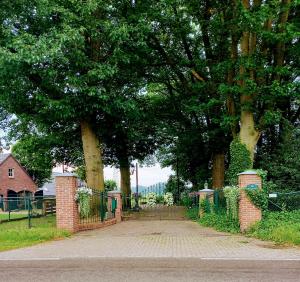 mooie familie groepsaccomodatie aan de bosrand في Overloon: بوابة في حديقة فيها اشجار وسياج