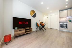 a living room with a television and a kitchen at Modern 1 Bedroom Apartment in the center of Bedford in Bedford