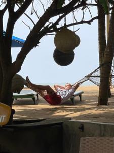 カルタラにあるHotel Coconut Bayの木の下にハンモックを敷く男