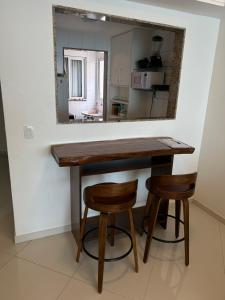 a kitchen with a table and two stools and a mirror at Apartamento de frente para o mar Praia do Morro Guarapari in Guarapari