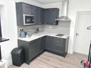 een keuken met zwarte kasten en een wastafel bij Homestay by BIC Legends 4 in Batley Carr